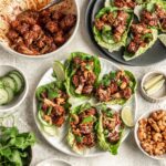 Deconstructed BBQ Tofu Cauliflower Lettuce Wraps. Several bowls of ingredients such as lettuce, bbq cauliflower and tofu, cucumber and cashews.