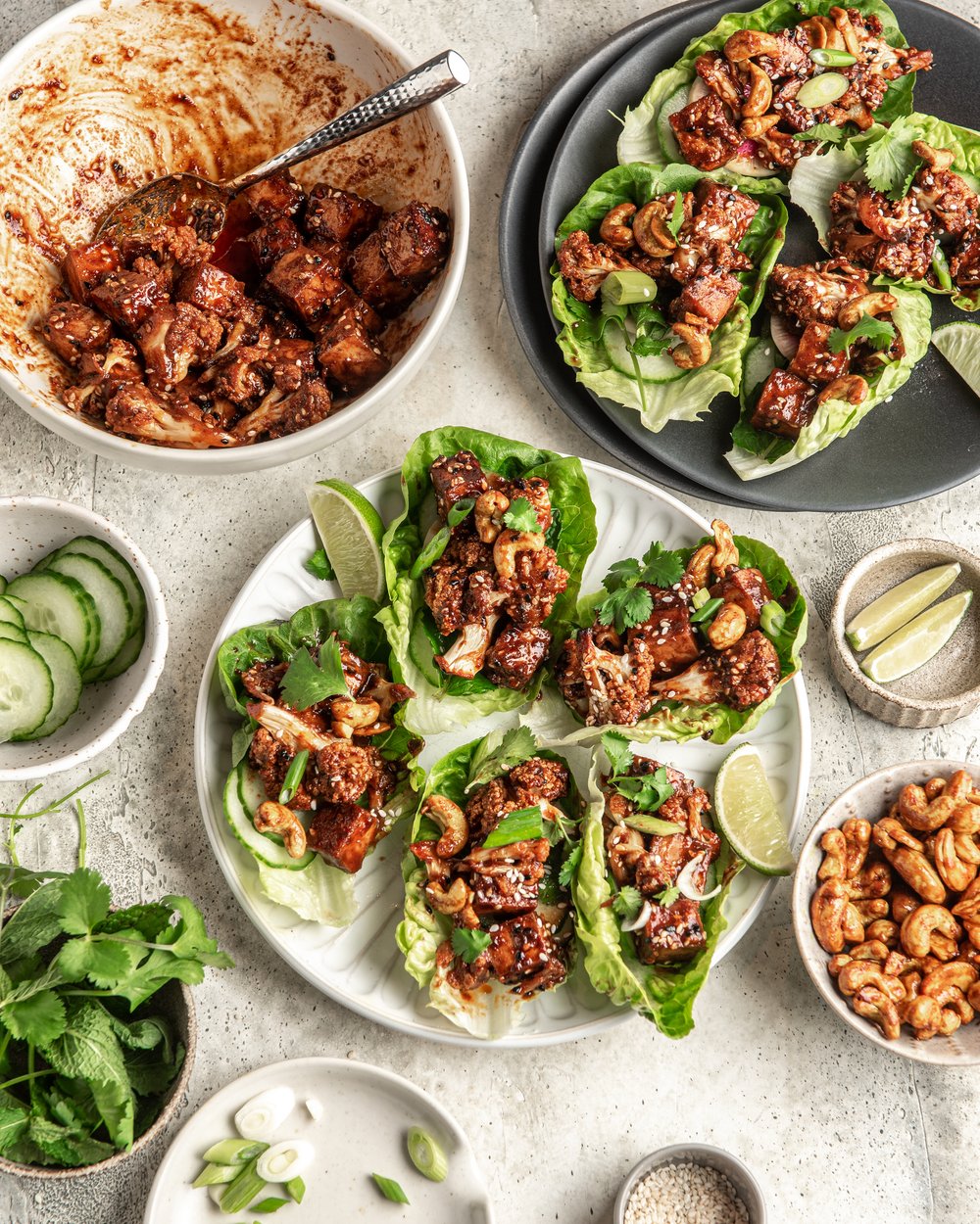 Deconstructed BBQ Tofu Cauliflower Lettuce Wraps. Several bowls of ingredients such as lettuce, bbq cauliflower and tofu, cucumber and cashews.