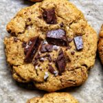 close up view of a freshly baked tahini chocolate chunk cookie with sea salt flakes by teri-ann carty