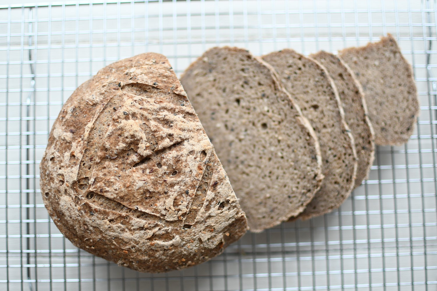 close up view of freshly baked seeded buckwheat flour sourdough bread with slices by teri-ann carty