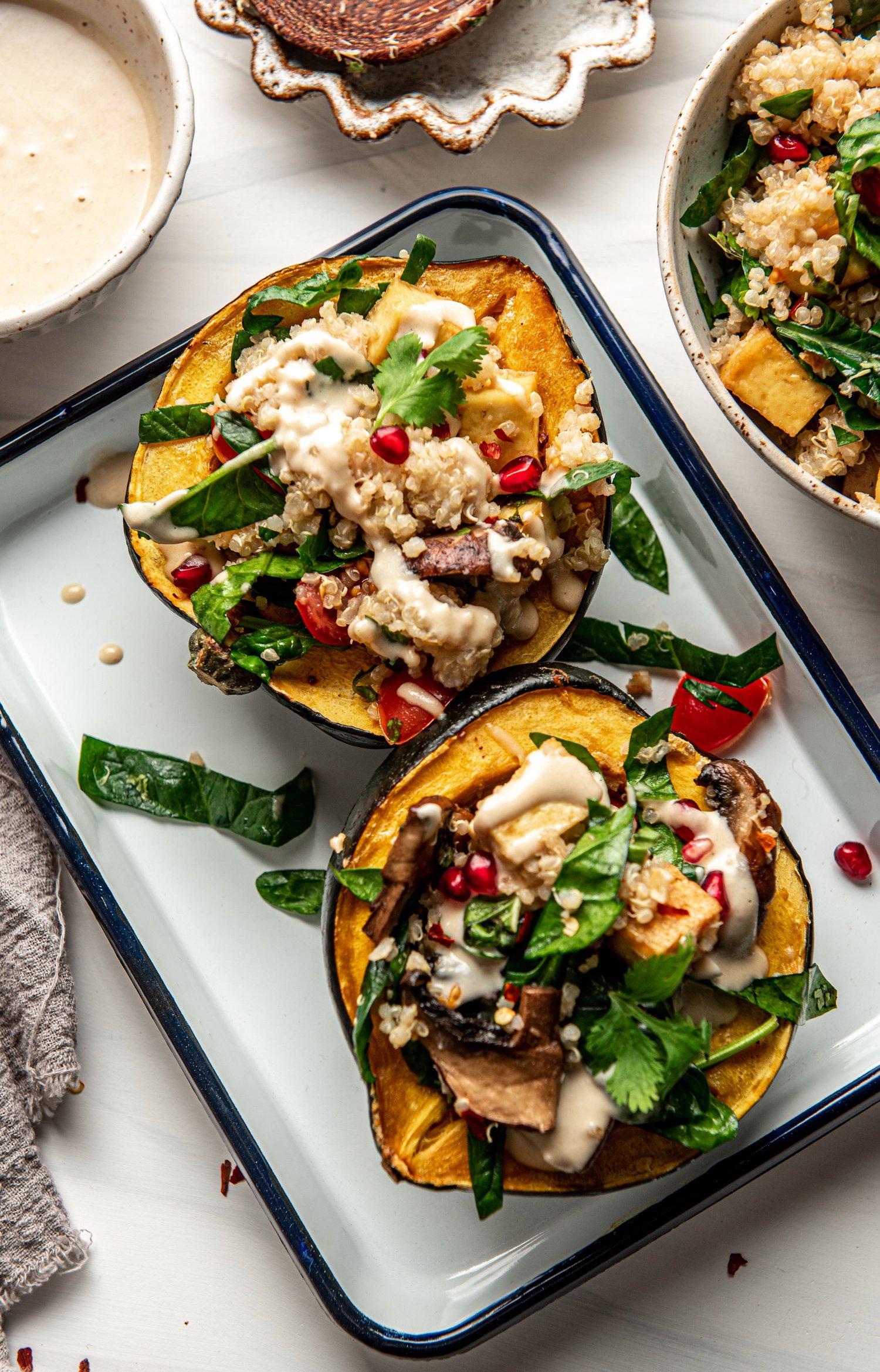 overhead view of vegetarian stuffed acorn squash with quinoa and creamy dip on top by teri-ann carty