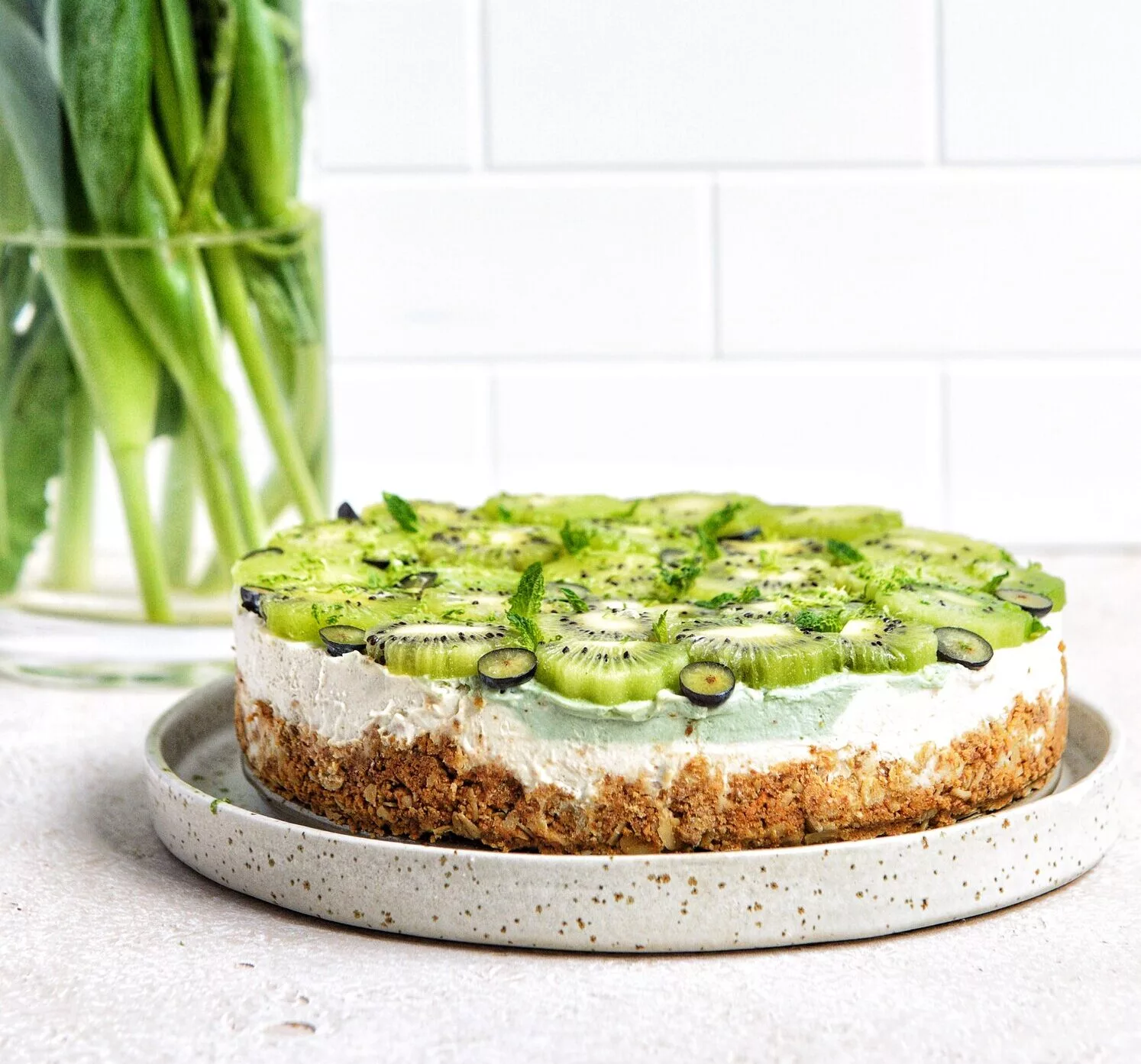 vibrant Vegan Kiwi Lime Cheesecake on a speckled plate