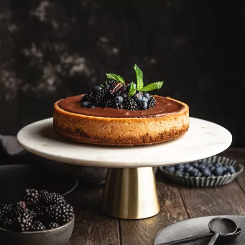 baked cheesecake with decorative plate. blackberries and blue berries on top
