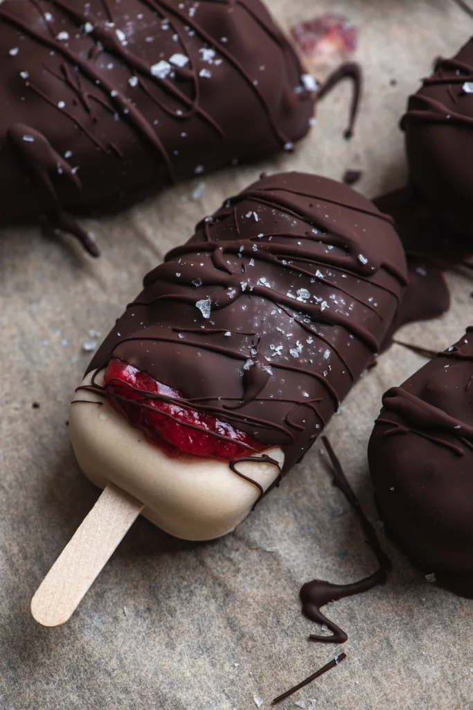 ice cream bar with strawberry jam oozing out of the chocolate dripped cover.