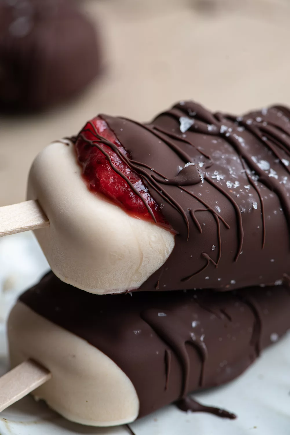 ice cream bar with strawberry jam oozing out of the chocolate dripped cover.