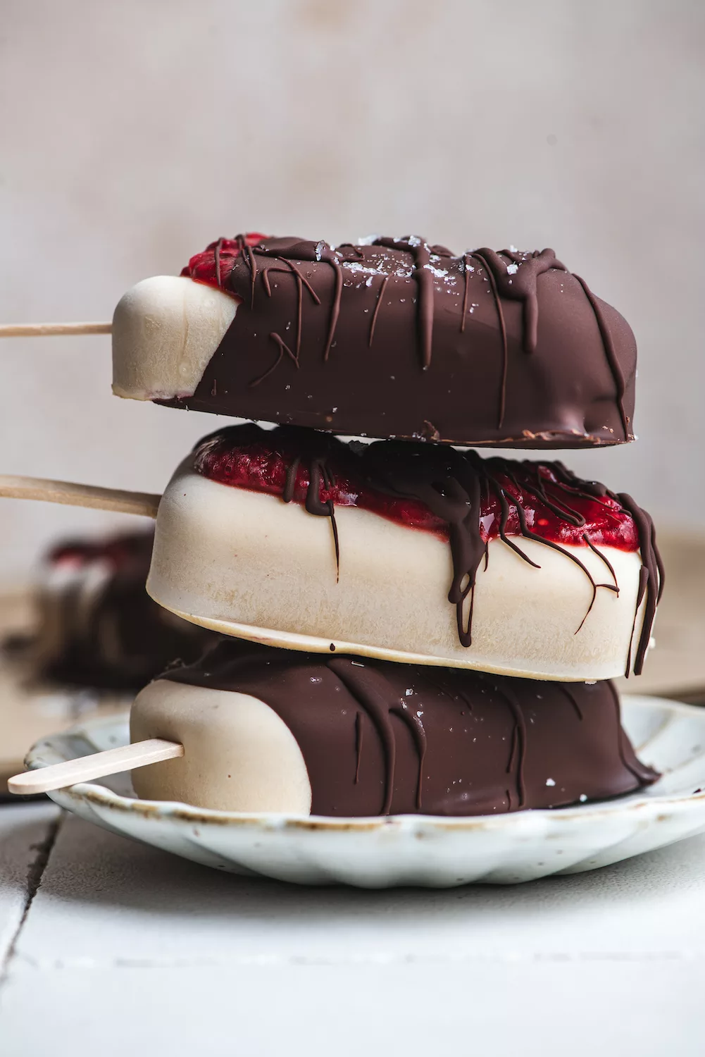a stack of ice cream bars with strawberry jam oozing out of the chocolate dripped cover.