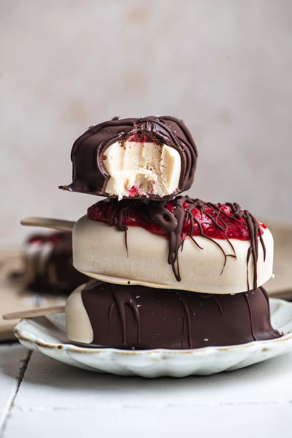 a stack of ice cream bars with strawberry jam oozing out of the chocolate dripped cover. top bar has a bite out of it