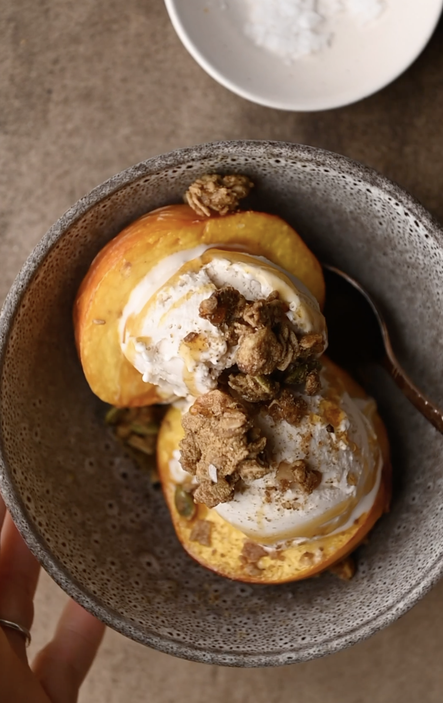 overhead view of grey bowl of air fryer peaches, with homemade ice cream and granola topping by teri-ann carty