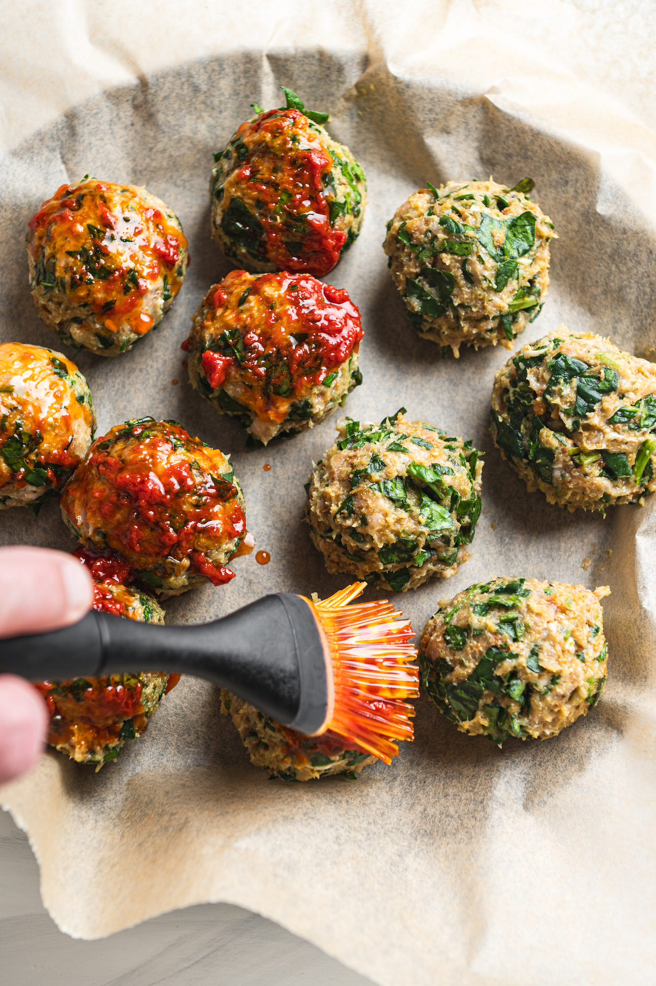 brushing tomato sauce on chicken meatballs by teri-ann carty