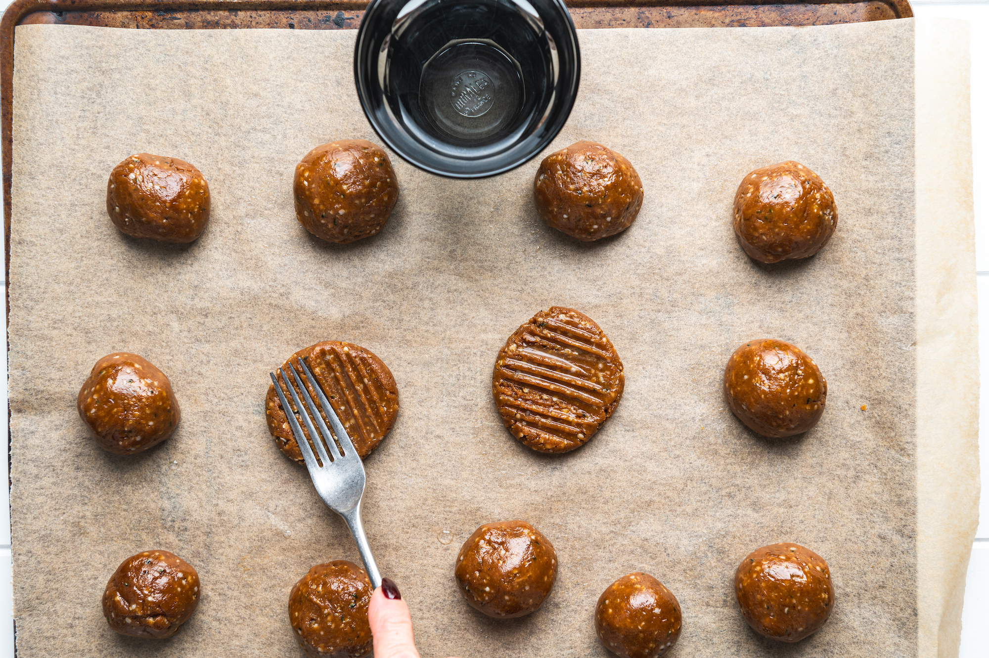 Overhead view with a fork mashing raw peanut butter cookies with seeds by teri-ann carty