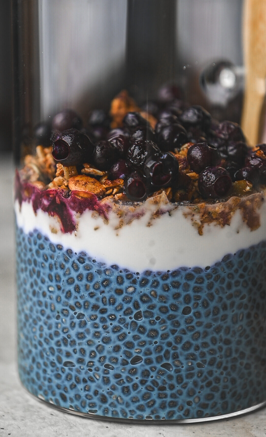 close up blue chia pudding, granola and blueberries topping by teri-ann carty
