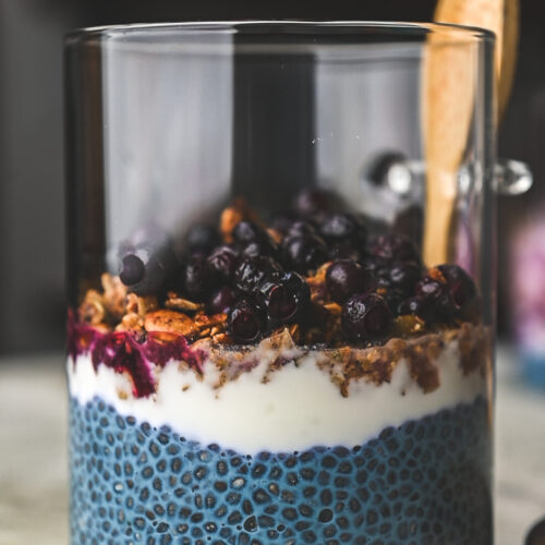Glass jar with blue chia pudding, granola and blueberries by teri-ann carty