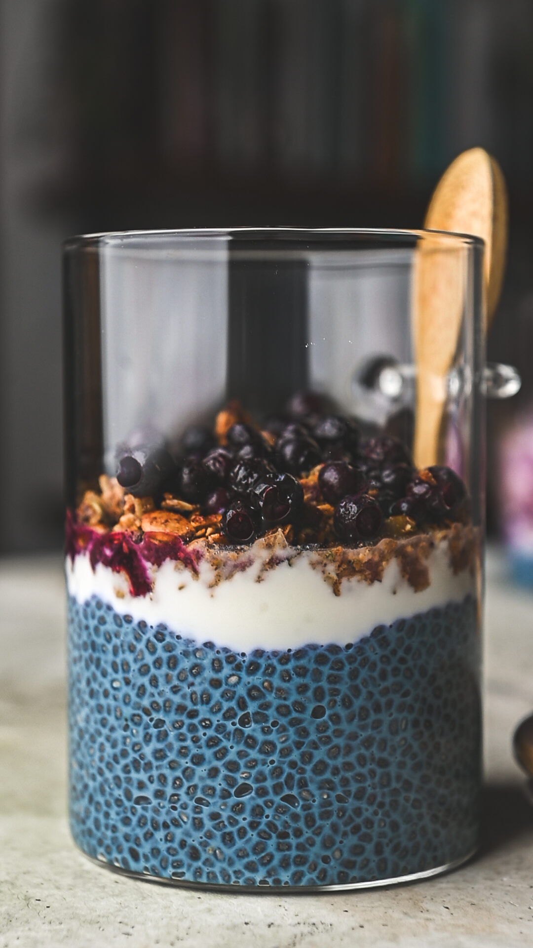 Glass jar with blue chia pudding, granola and blueberries by teri-ann carty