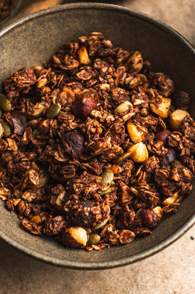close up of a bowl with crunchy nutella granola, chocolate nuts by teri-ann carty
