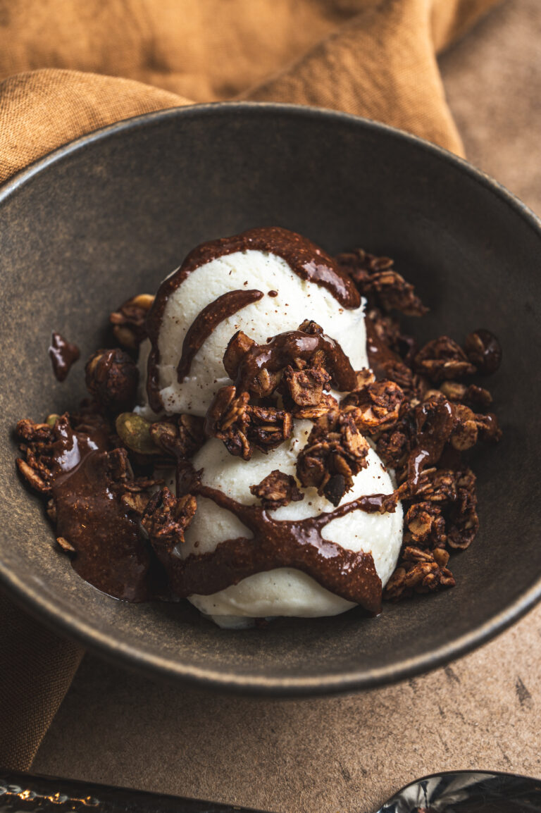 dark bowl with delicious dessert, ice cream covered in liquid nutella and nutella granola for the topping by teri-ann carty