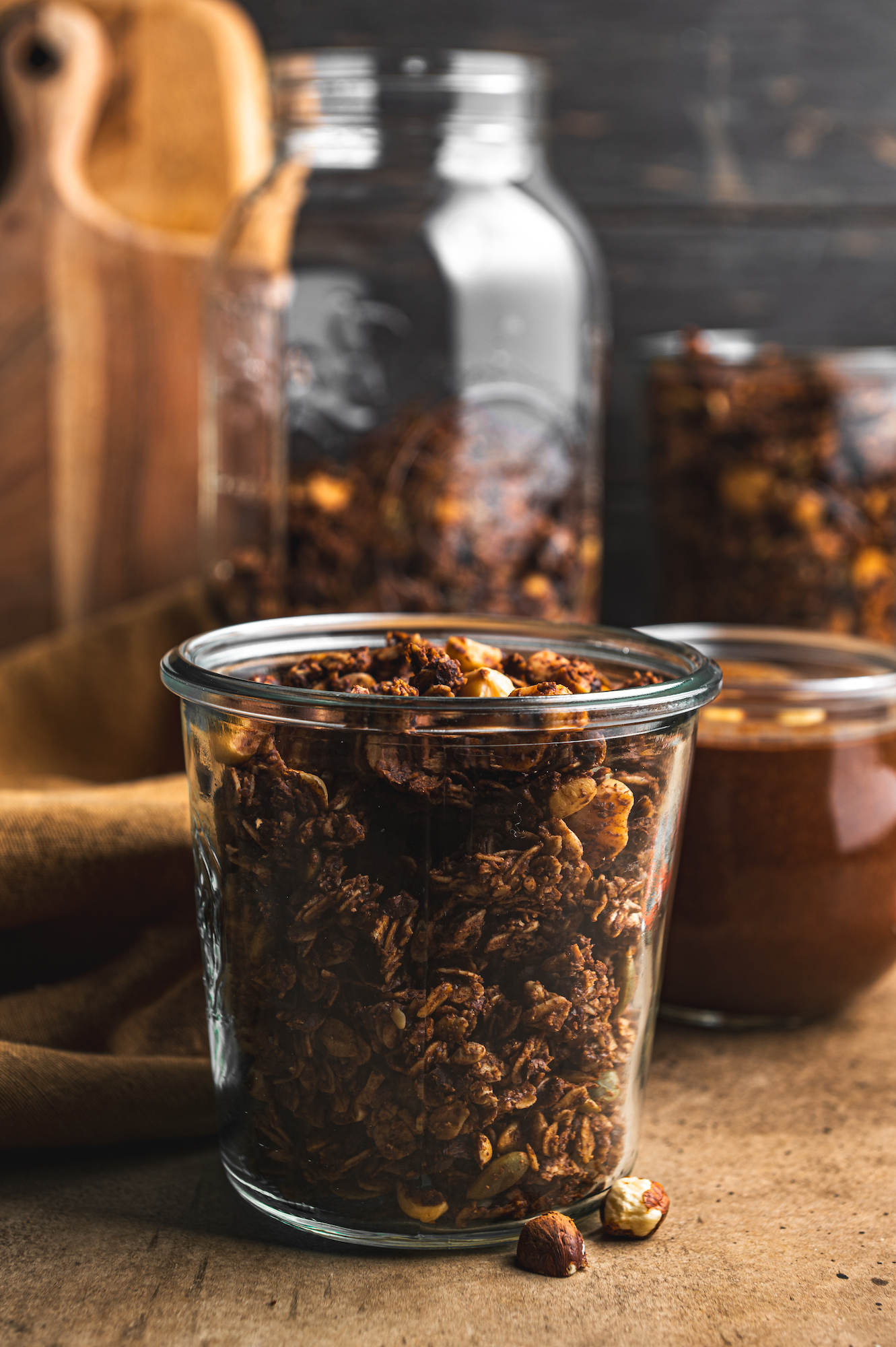 glass jar filled with crunchy nutella granola on brown tones by teri-ann carty