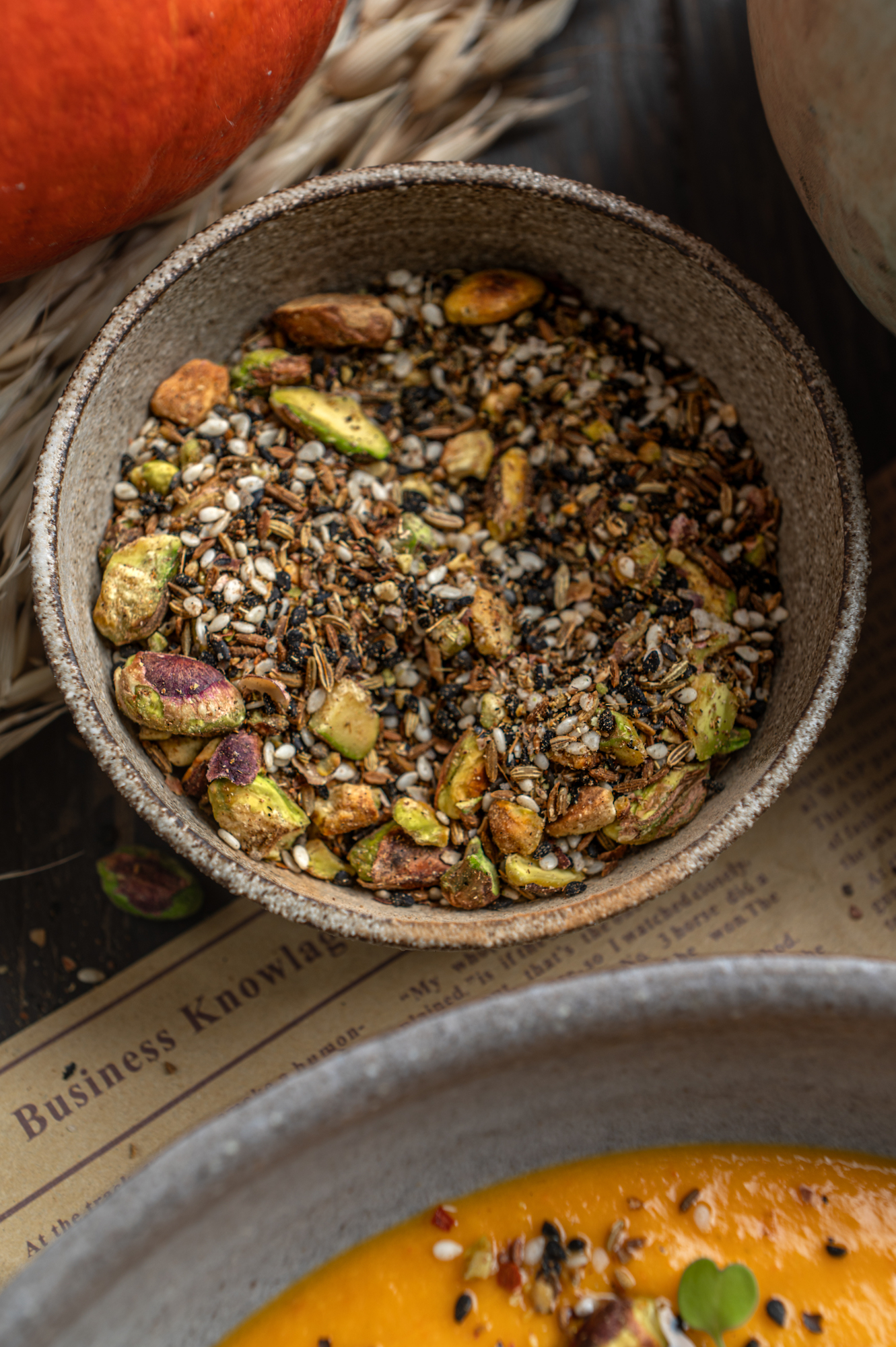 bowl with seeds, spices, pistachios, sesame, the ingredients for pumpkin tomato soup by teri-ann carty