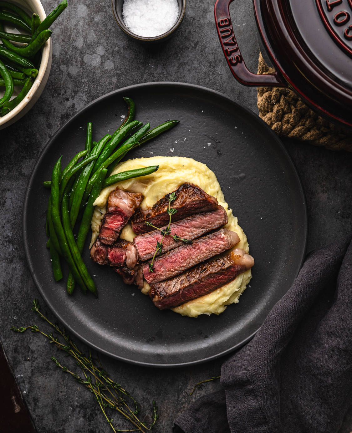 creamy mashed potatoes with sliced steak and some greens