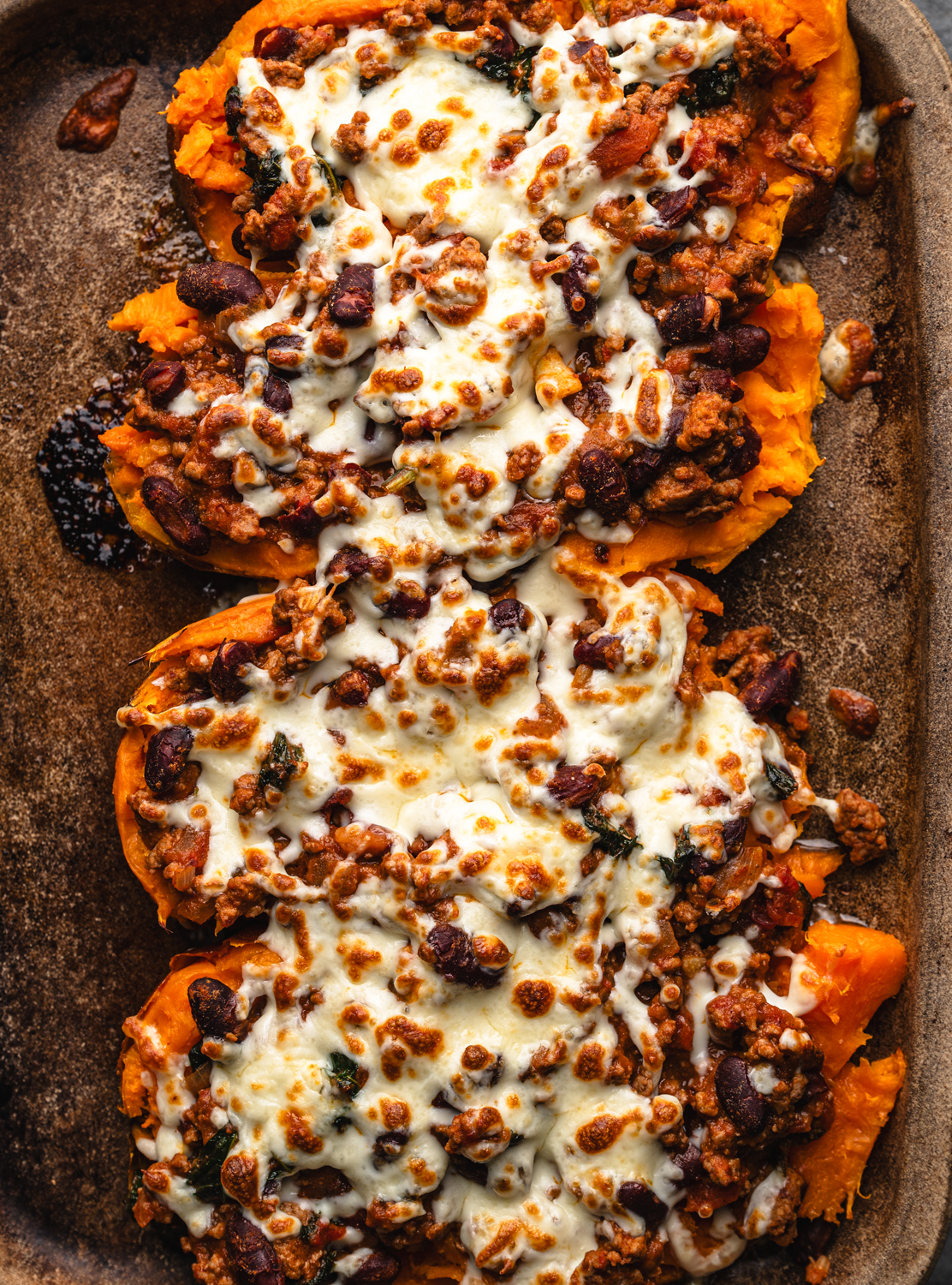 roasted sweet potato halves topped with beef and bean chili and melted cheese
