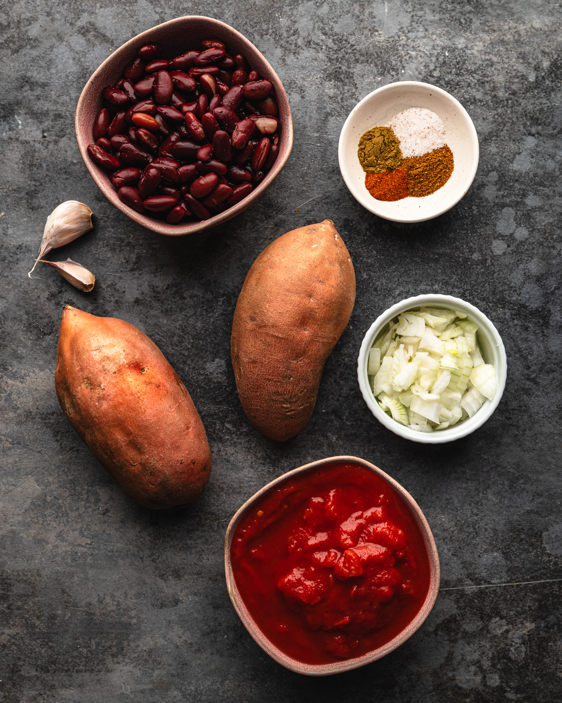 bowls with beans, sweet potatoes, onion, spices, tomato paste and garlic.