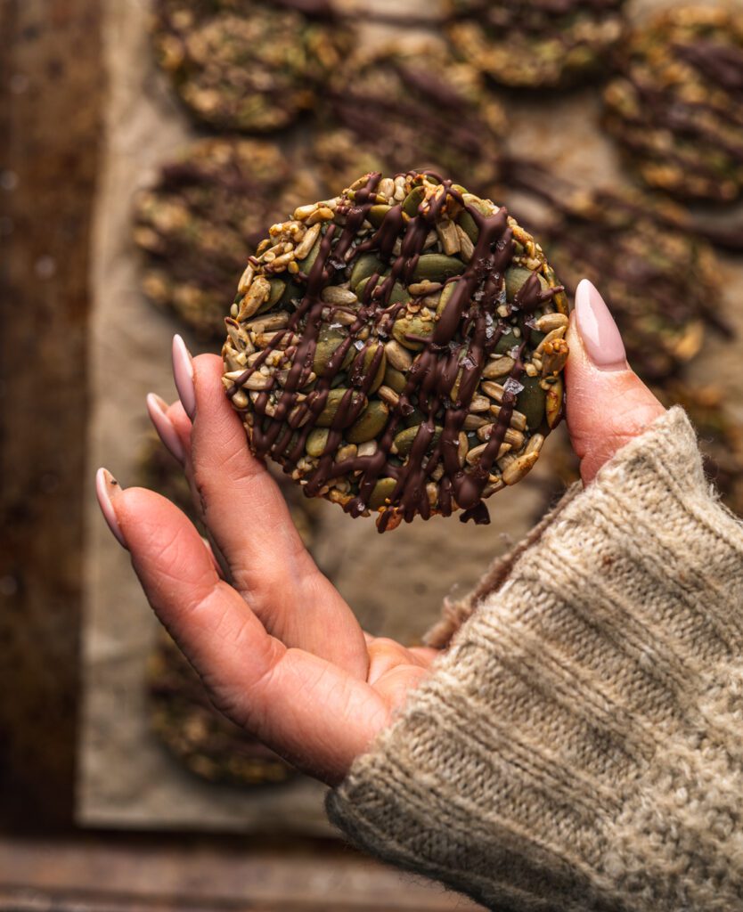 womans hand holding chocolate covered healthy cookie