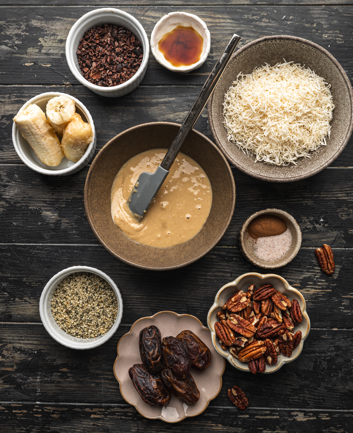 banana date bliss ball ingredients including banana, dates, pecans, coconut, hemp seeds, cacao nibs, and maple syrup