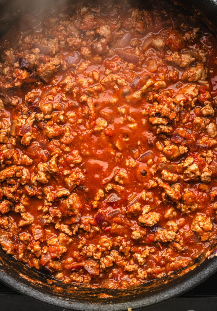 close up of ground chicken in tomato sauce simmering