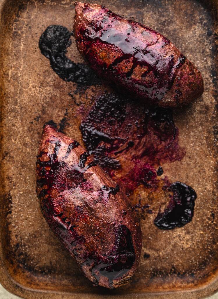two purple sweet potatoes baked on a stone pan