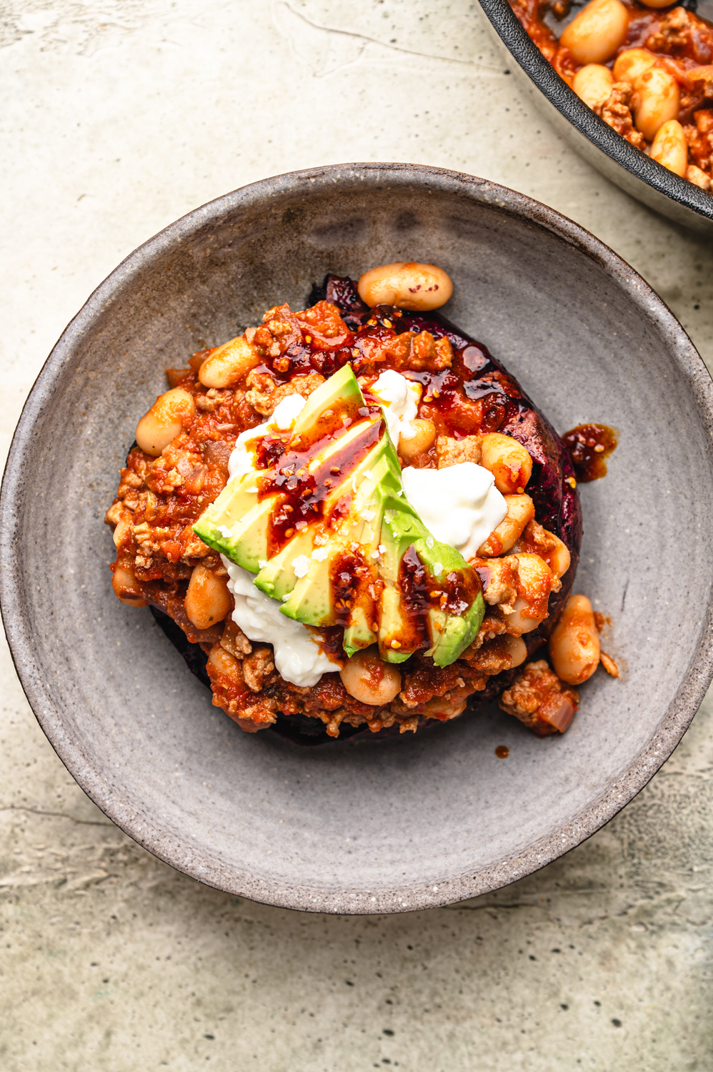 large ceramic bowl filled with high protein stuffed sweet potatoes loaded with ground beef, white beans, avocado and cottage cheese