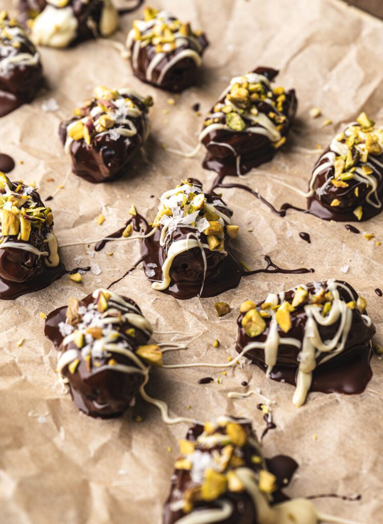 freshly chocolate dipped and drizzled pecan stuffed dates on parchment paper