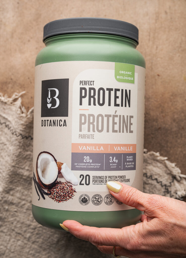 female hand holding botanica protein powder container
