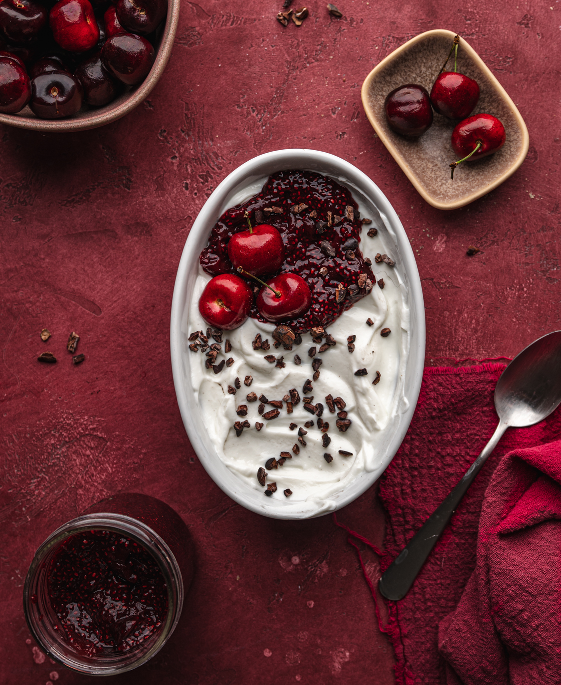 overhead perspective of black forest overnight oats in a large ramkein topped with cherries, cacao nibs and homemade cherry chia jam