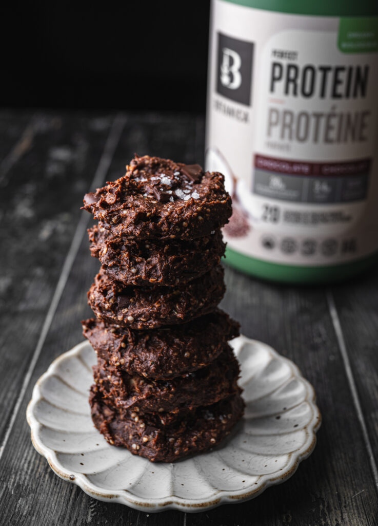seven flourless high protein nutella cookies stacked high on a white scalloped plate