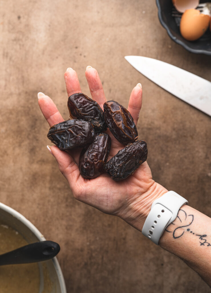 a hand holding five medjool dates