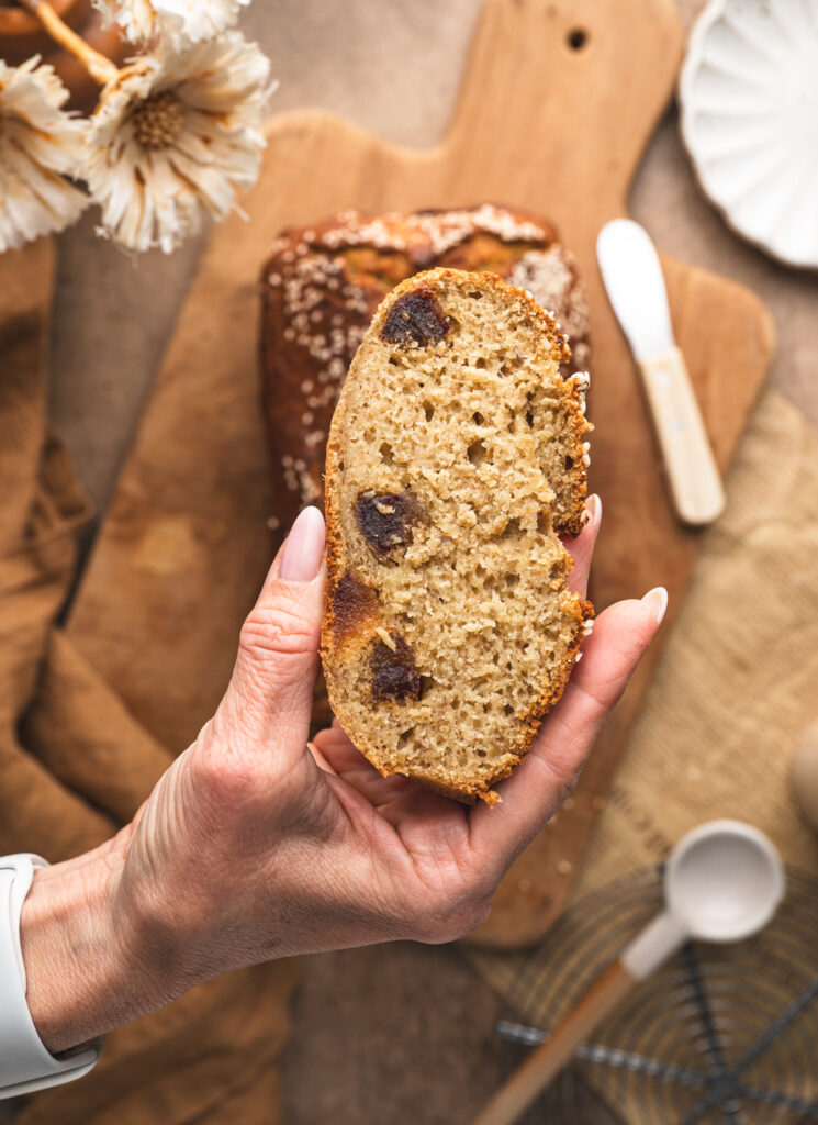 hand holding a slice of banana and date bread