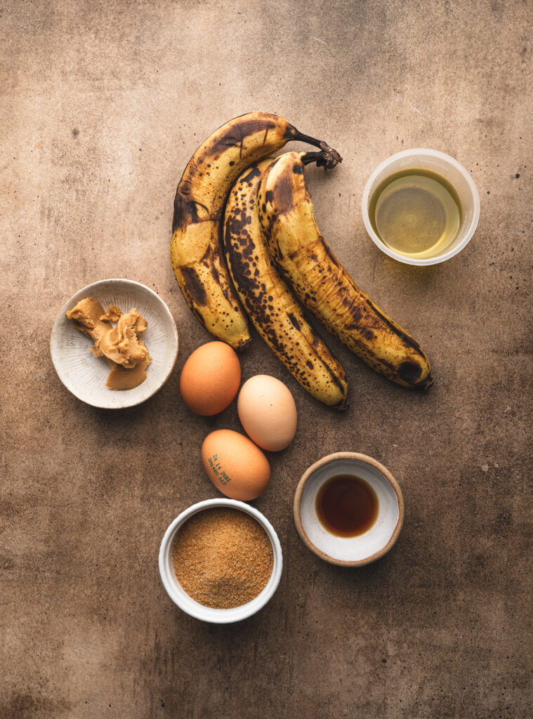 ingredients to make date and banana bread, spotted ripe bananas, sugar, vanilla, eggs, oil and some white miso paste