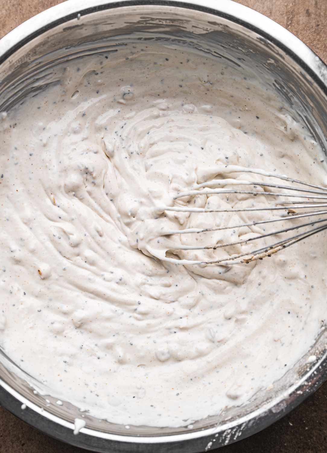 creamy mocha ice cream mixture with chia seeds being whisked in a metal bowl
