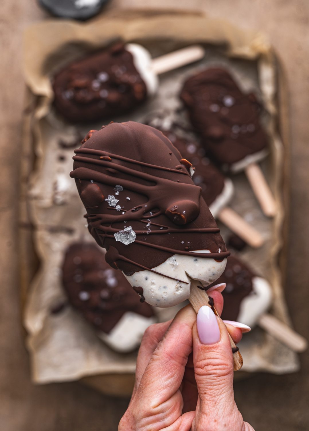 close-up of a chocolate-dipped mocha ice cream bar with a drizzle of chocolate and sea salt