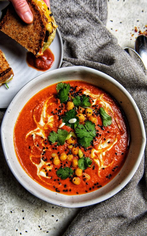 bowl of tomato soup with cilantro and chickpea topping and a grilled cheese on the side by teri-ann carty